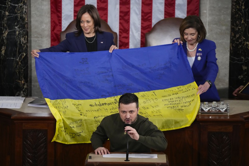 烏克蘭總統澤倫斯基（下）送給美國國會一面烏克蘭國旗，上面寫滿了前線作戰的烏國士兵簽名。美聯社