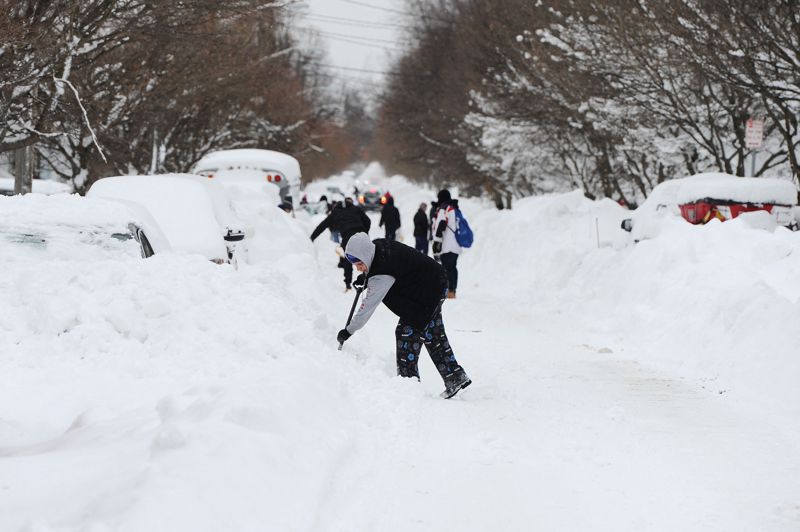 美國紐約州水牛城去年耶誕假期遭冬季暴風雪襲擊， 圖為居民在街上剷除幾乎將車輛埋沒的積雪。法新社