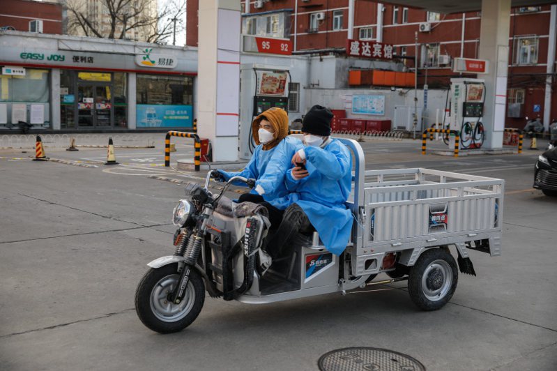中國大陸民眾上月十五日戴著口罩騎三輪車經過北京街頭。國際貨幣基金總裁喬治艾娃警告，大陸新冠疫情迅速蔓延，短期內經濟將面臨新一波打擊。（歐新社）