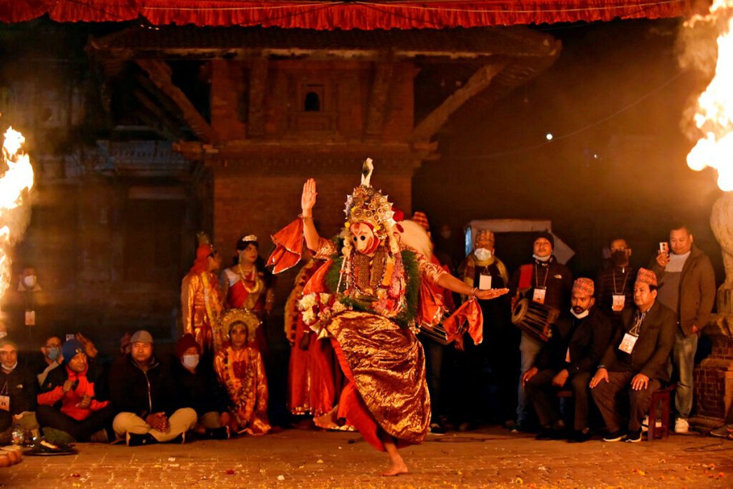 一名戴著白獅面具的舞者，手腕和手肘上上綁著紅色布條，長長的鬃毛垂在後腰，映著舞臺...
