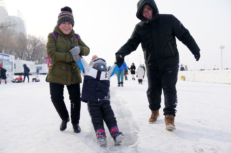 中國大陸黑龍江漠河冷到零下五十三度，打破大陸最低溫紀錄。圖為哈爾濱，家長帶孩子玩雪。（新華社）
