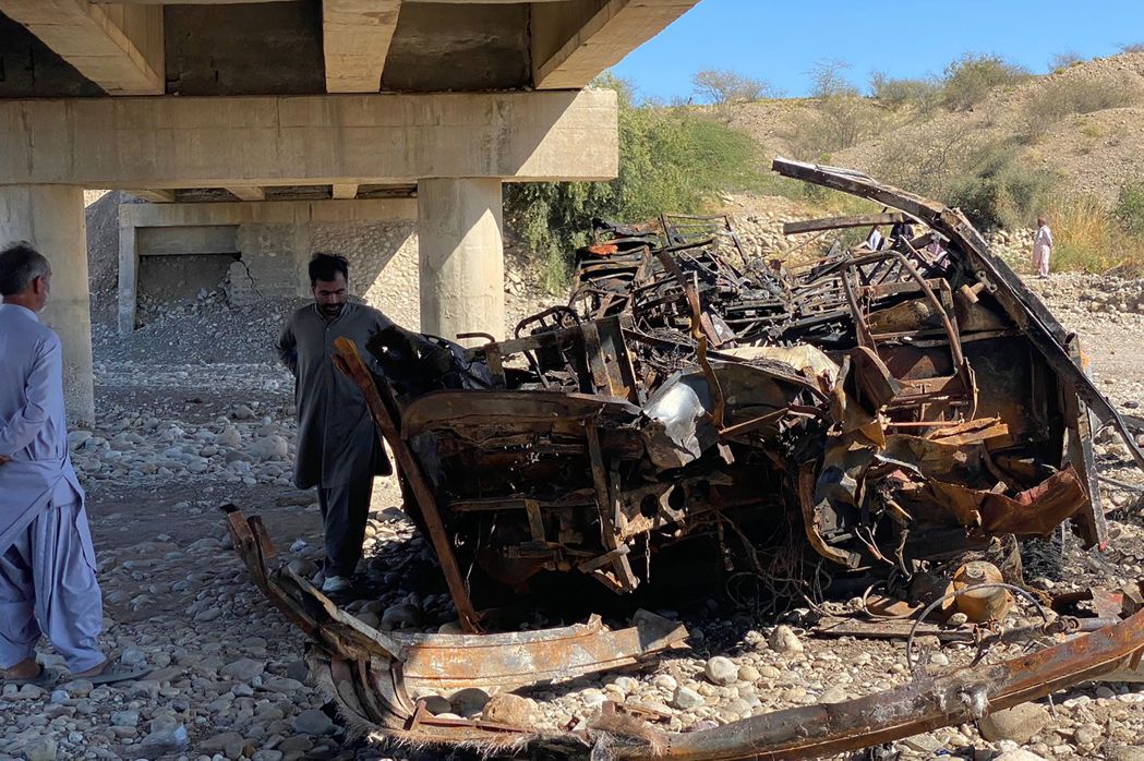 巴基斯坦南部俾路支省一輛公車29日墜谷起火，當地居民正檢視殘骸。法新社