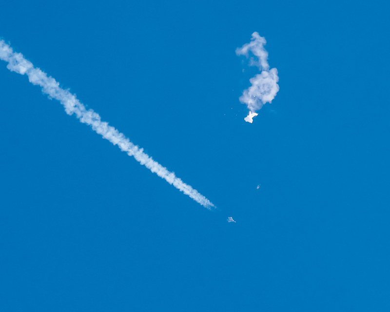 目擊者提供的照片顯示，大陸間諜氣球四日在南卡州被飛彈擊中後殘骸下墜，一架美軍戰機從下方掠過。（美聯社）