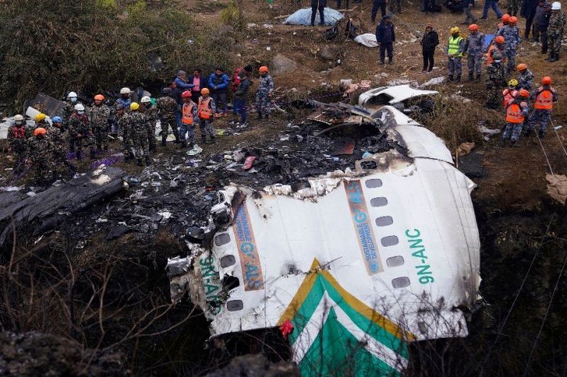 尼泊爾雪人航空ATR客機15日墜毀，救難人員站在客機殘骸旁。美聯社