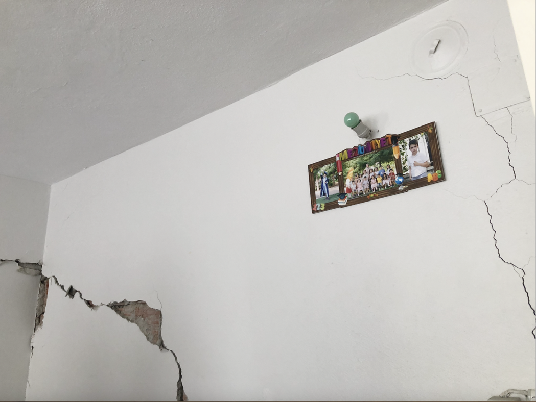 重返地震災民的住所，龜裂的牆上還貼著孩子的照片。 圖／作者李姿萱拍攝　　　