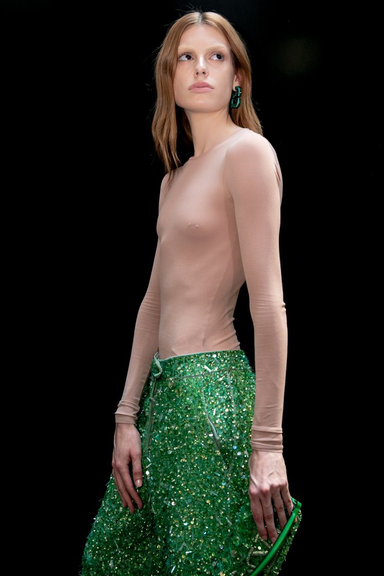 綴滿亮片的皺摺長裙展現源自高級訂製服的工藝，鮮豔的綠色配襯裸膚色緊身上衣對比反差...