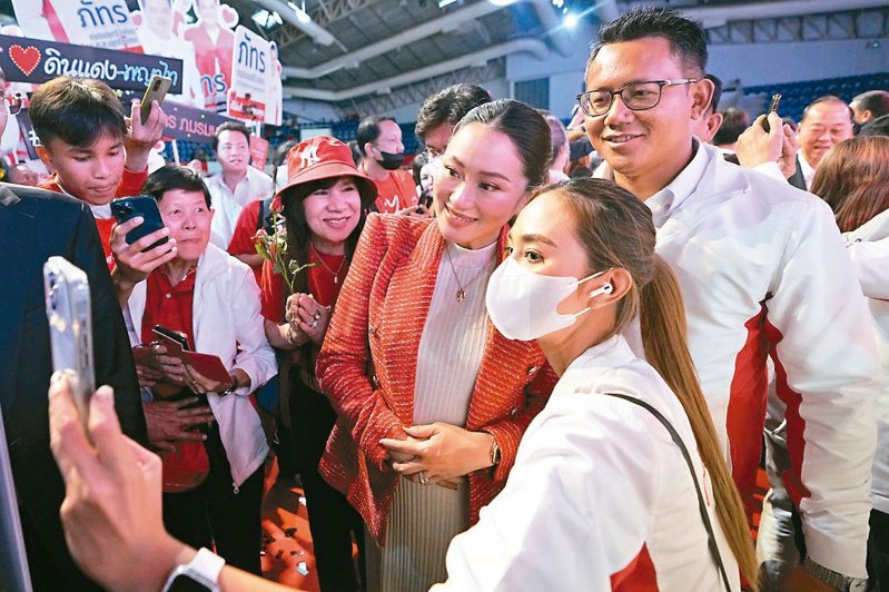 泰國最大在野黨為泰黨可能總理候選人貝東塔（右三）十七日發表談話，一名支持者開心找她自拍留念。（美聯社）