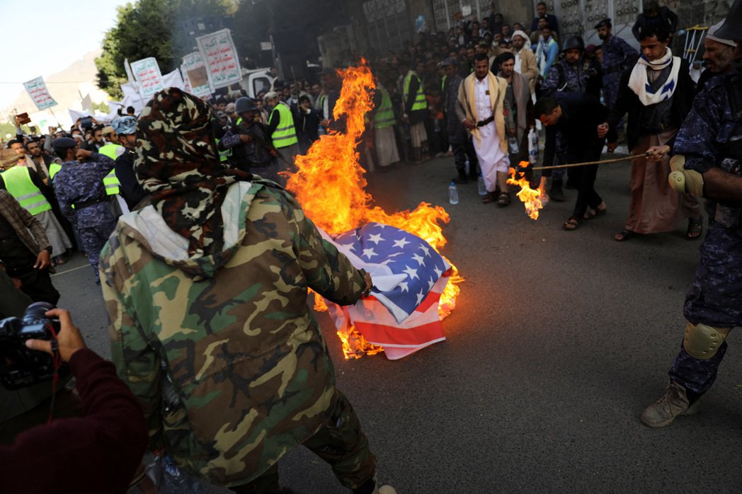胡塞武裝組織支持者在一場集會上焚燒美國國旗。 圖／路透社