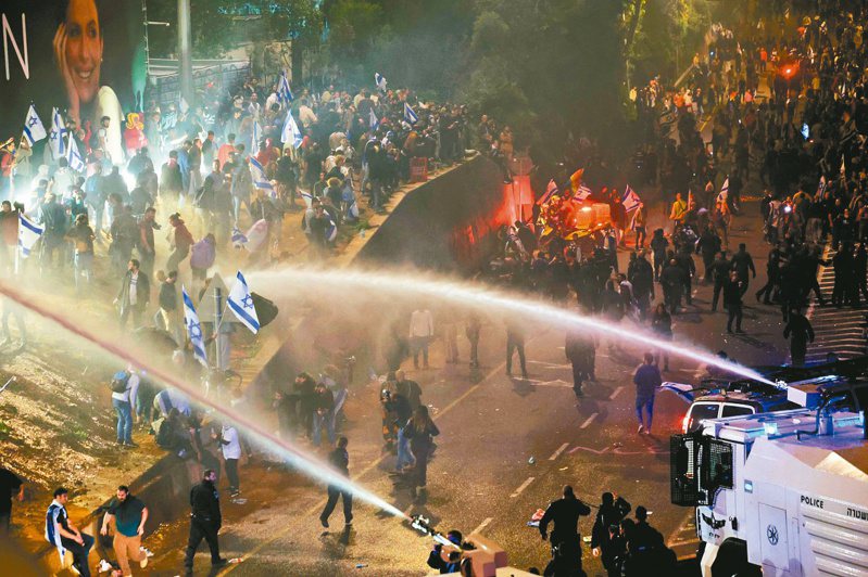以色列總理內唐亞胡強推高爭議的司改案，引發警民對峙。警方廿七日以強力水柱驅散示威群眾。（法新社）