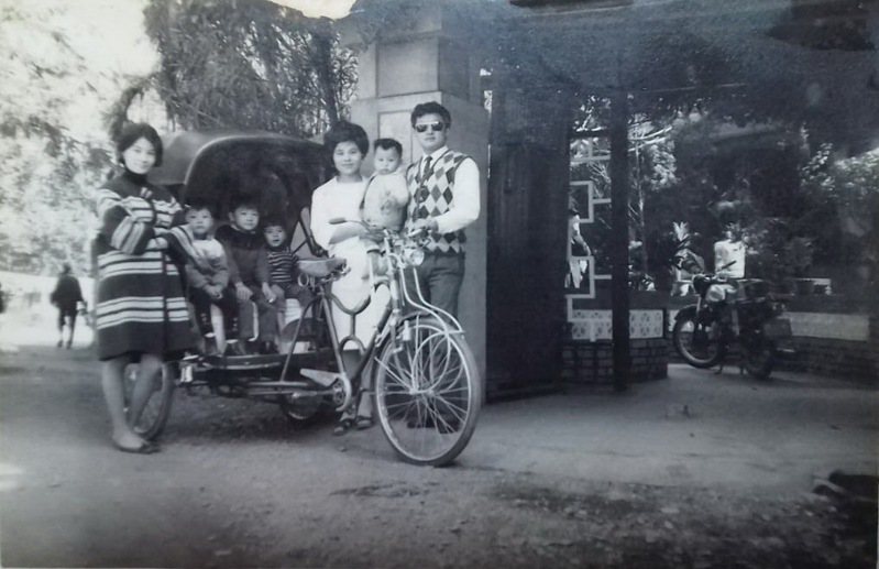 六歲以前，作者家裡頭也曾經擁有過一輪黑色頂蓬的三輪車，站在畫面右邊的正是作者的爸、媽，襁褓中的作者當時還不足兩歲。（照片攝於1968年）。圖／NEWS