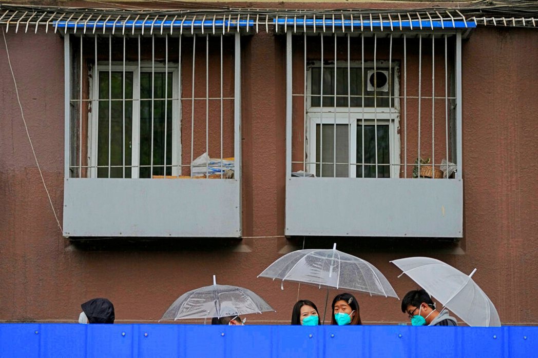 被封控的居民，雨中在公寓圍欄內等待進行核酸檢測，非本文當事人。 圖／美聯社　　