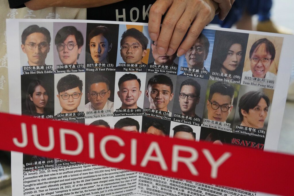 圖為今年3月香港民主派47人初選案開審，場外支持者手持帶有部分該案被告相片的看板。 圖／美聯社