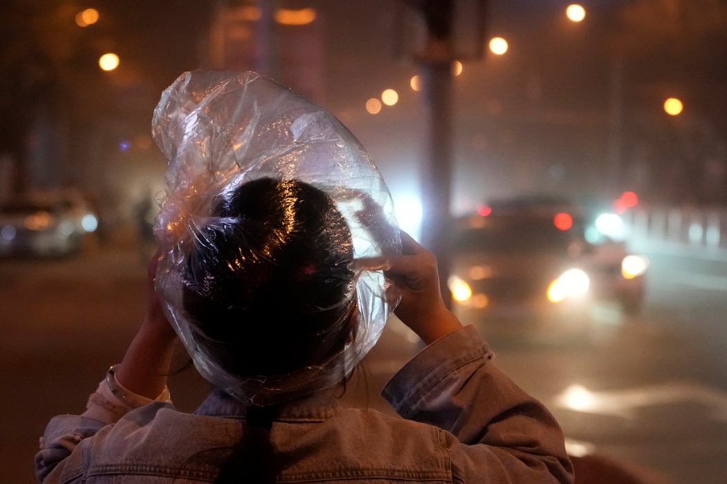 2023年4月11日，北京一名居民以塑膠袋套頭來抵擋空氣中的沙塵。 圖／美聯社