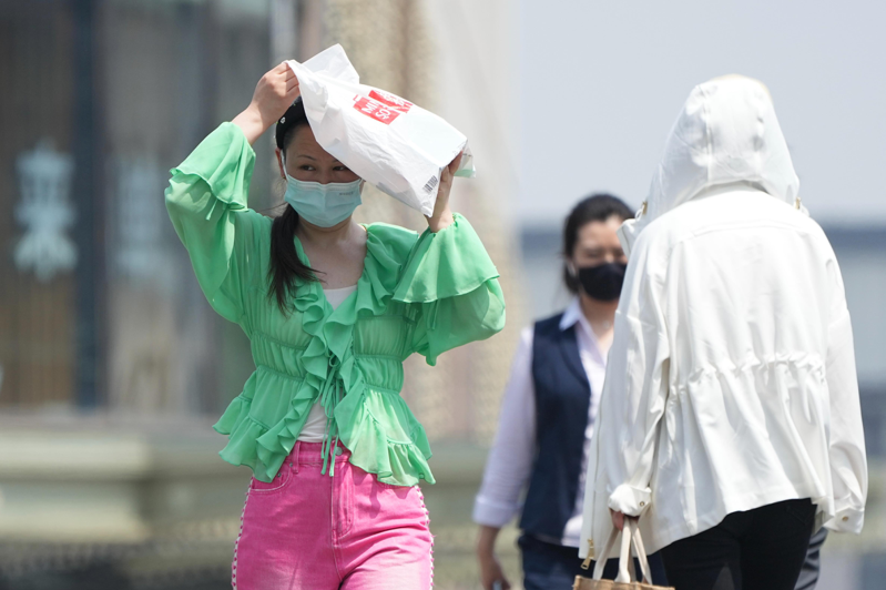 5月中旬，北京就已出現35、6度高溫，讓不少民眾擔心今年夏天是否還會讓大家「熱哭」？圖為15日，北京街頭一名女子用購物袋遮陽。（中新社）