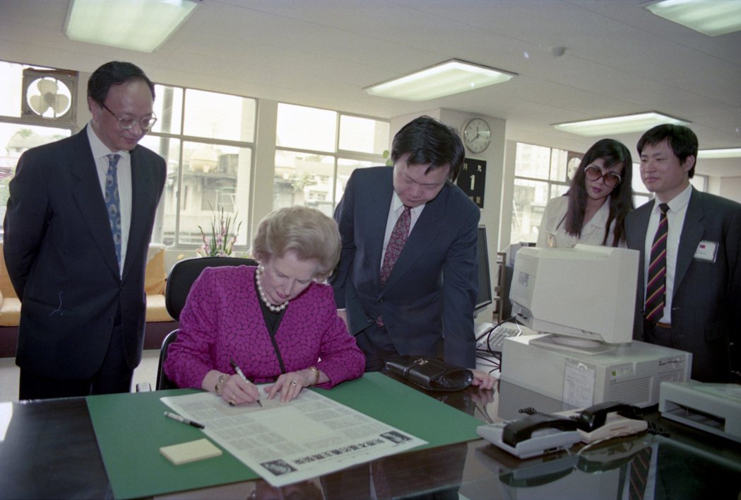 1992年柴契爾夫人到訪聯合報，在報紙版面上親筆簽名。左立者為時任聯合報系副董事長王必成。 圖／聯合報系資料照