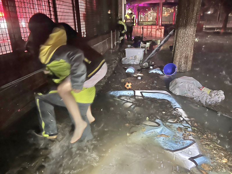 竹北沿海今晨淹水情況嚴重，消防人員更人力背民眾撤離危險淹水區域。圖／新竹縣消防局提供