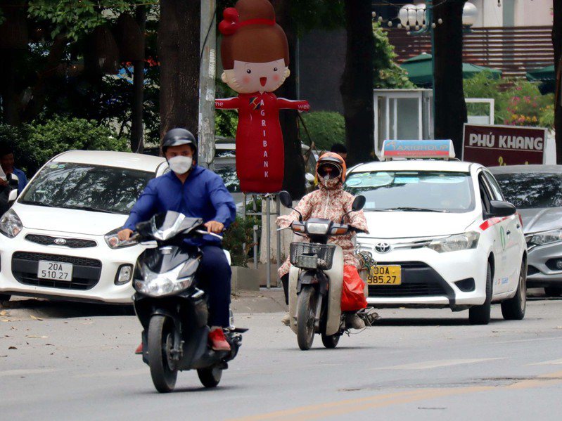 越南多地5月就出現攝氏40度以上高溫，越南官方警告缺電危機。圖為越南民眾在豔陽下全身包緊緊騎機車，深怕曝晒。圖／中央社