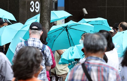 領到中鋼股東會紀念品的民眾撐起傘的照片。記者侯永全／攝影