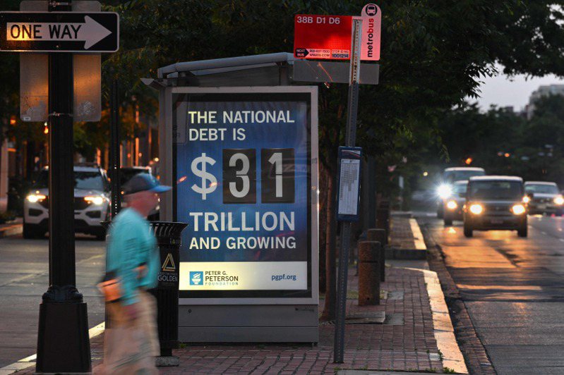 美國華盛頓街頭一處公車站旁的告示牌，顯示美國國債已超過卅一兆美元。（法新社）