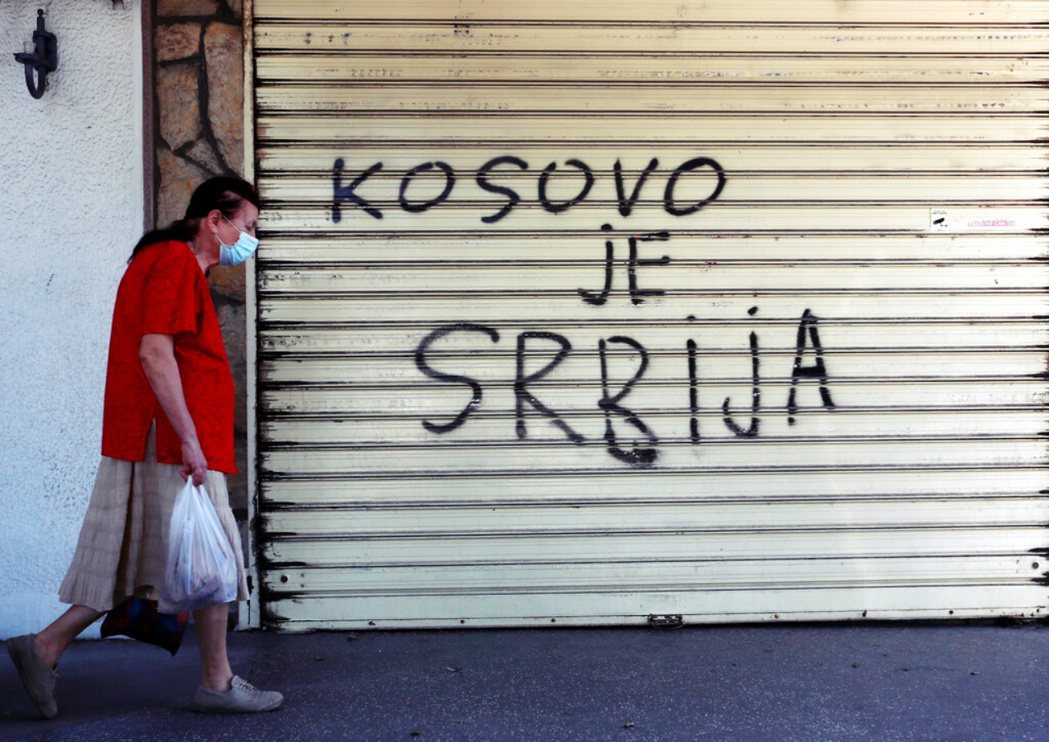 圖為2020年，一位婦女路過寫著「科索沃是塞爾維亞」的塗鴉。 圖／美聯社