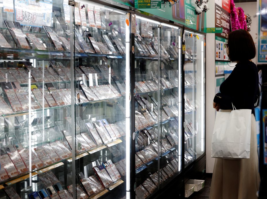 圖為民眾在二手手機店鋪挑選櫃內陳列的舊款手機，圖為示意圖，攝於日本東京秋葉原。圖／路透