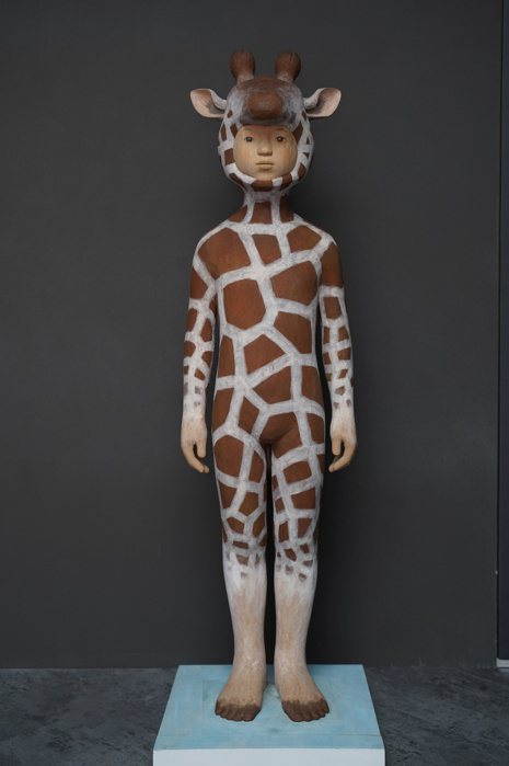 小泉悟《動物人 - 長頸鹿》：用日本的木雕工藝，保留質樸的刻痕，動物的衣著有神秘...