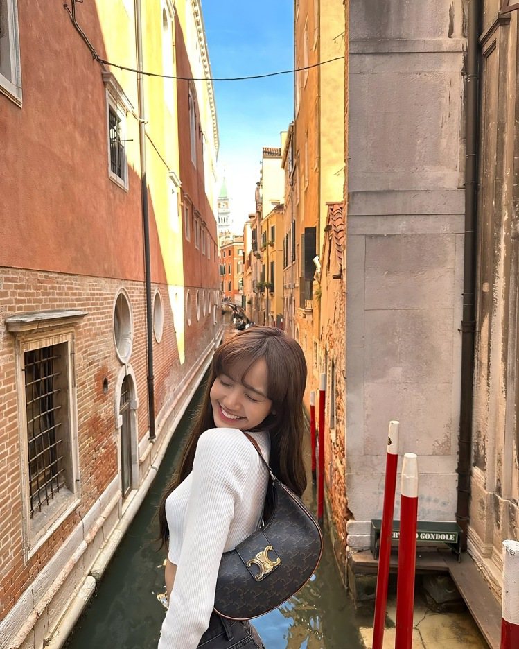 LISA拎新款AVA TRIOMPHE標誌印花小牛皮包造訪威尼斯。圖／摘自藝人I...