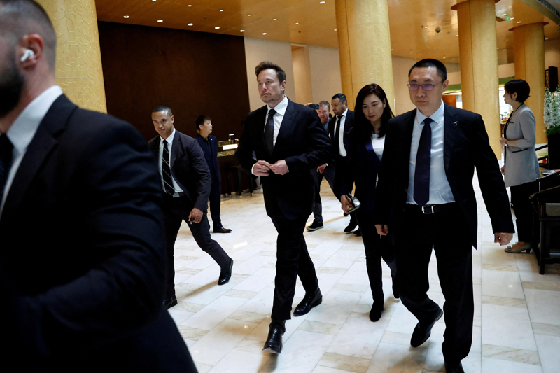 馬斯克（中）5月31日在北京離開飯店時，緊跟在馬斯克身旁的西裝男就是朱曉彤（右）。路透