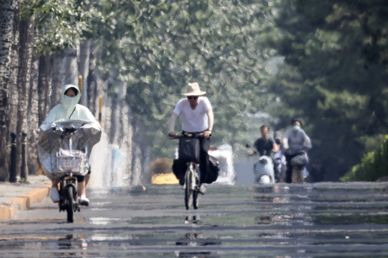 圖為6月16日，北京市民在烈日下騎車，當日的最高氣溫飆到39℃。  中通社