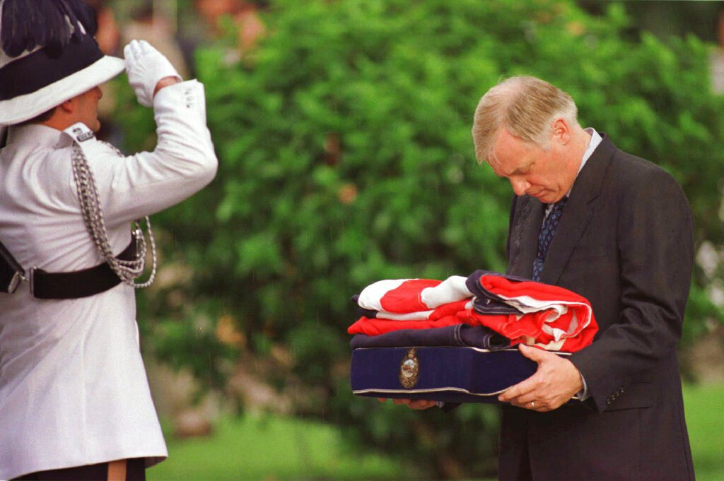 圖為彭定康在離開港督府的儀式上握著摺疊的英國國旗，一名副官向他敬禮。 圖／美聯社