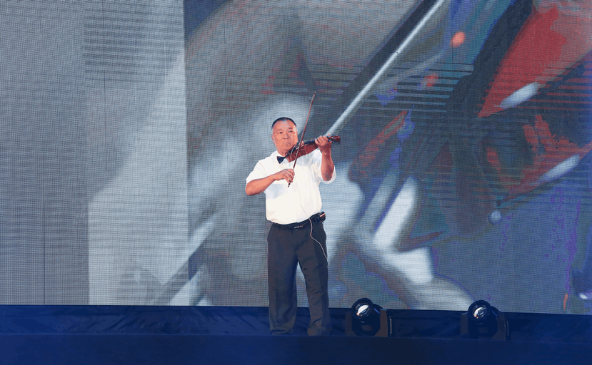 呂振裕站在小巨蛋的舞台上，在萬名觀眾面前演奏小提琴。 圖／弘道老人福利基金會提供