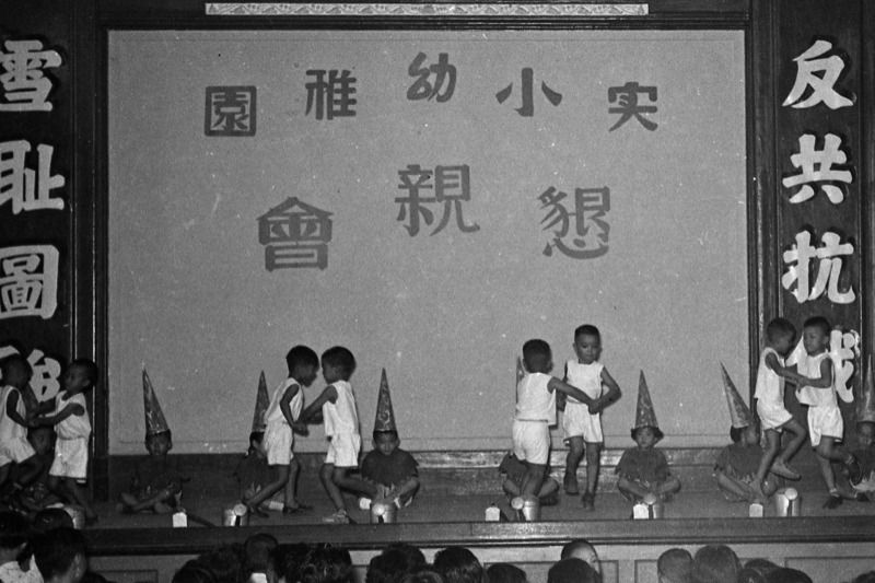 1954年7月4日，國語實小幼稚園舉辦畢業典禮懇親會，小朋友表演的舞台上有反共抗俄的標語。圖／聯合報系資料照片