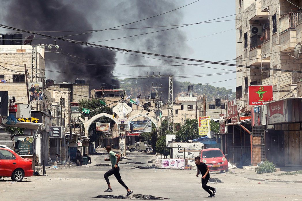 在傑寧的衝突中，巴勒斯坦青年在街頭奔跑尋找掩護。 圖／法新社