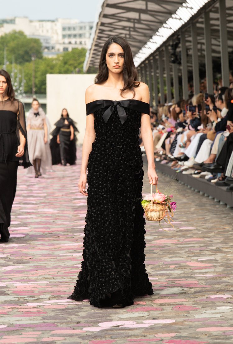 綴滿立體花朵的黑色絲絨長禮服，搭配70年代巴黎女性愛用的竹編籃。圖／香奈兒提供