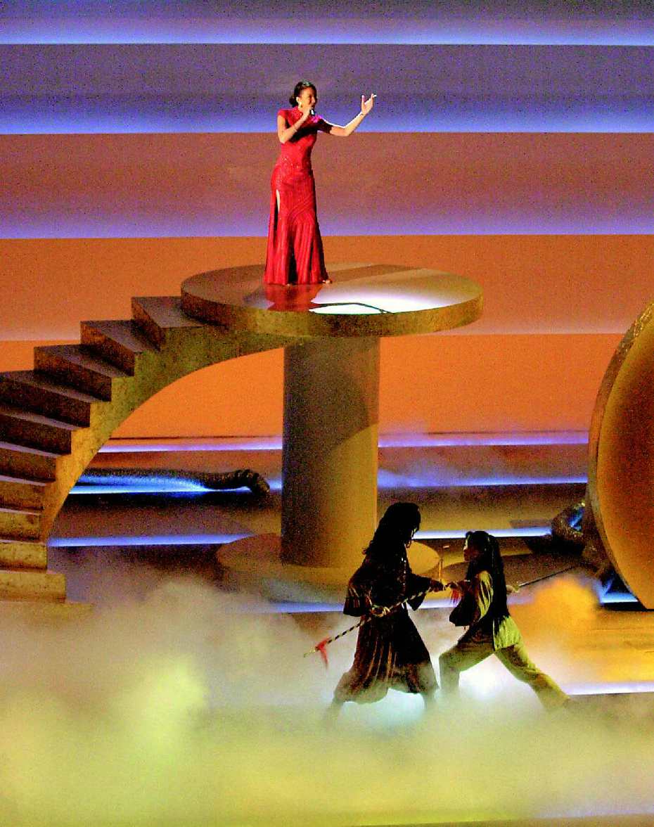 歌手李玟在奧斯卡頒獎典禮上演唱入圍最佳電影歌曲的「月光愛人」，這首歌是「臥虎藏龍」主題曲。右下角兩名人員表演中國武術打鬥。(路透)