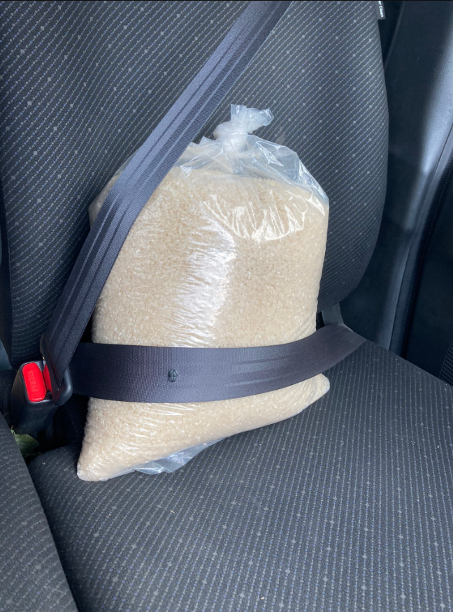 一名日本網友因為車內系統發出警報聲，幫一大袋米繫上安全帶。圖／擷自推特