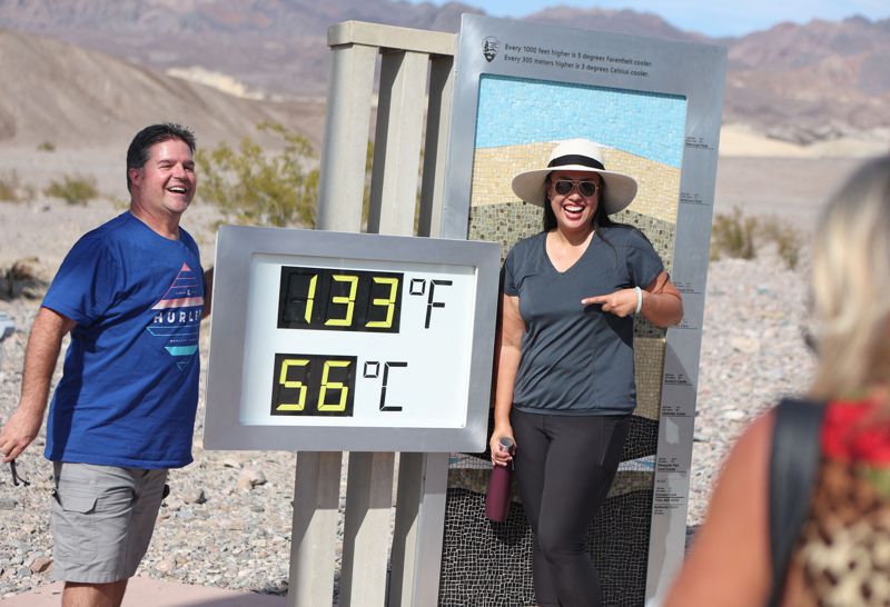 加州死亡谷火爐溪遊客中心外知名的溫度展示器16日顯示氣溫達攝氏56度，特地前往感受高溫的遊客開心留影。法新社