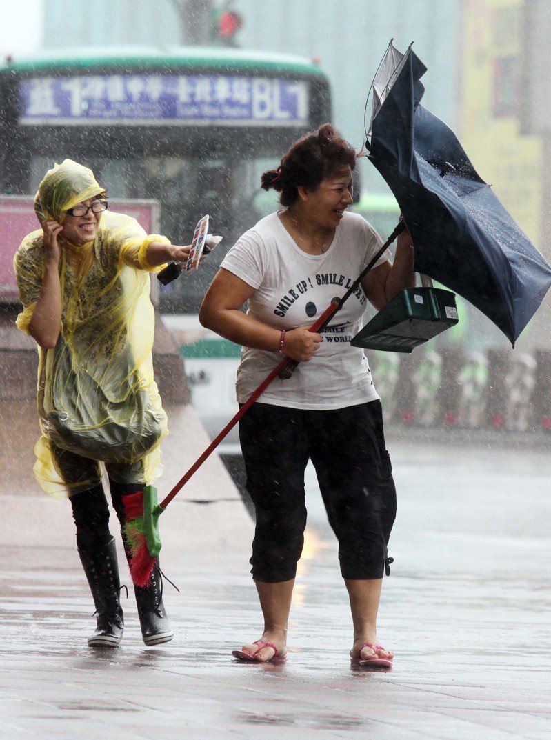 圖為多年前某場颱風，路上行人雨傘開花，電視台記者冒著強風暴雨忙做採訪。記者高彬原攝影／報系資料照