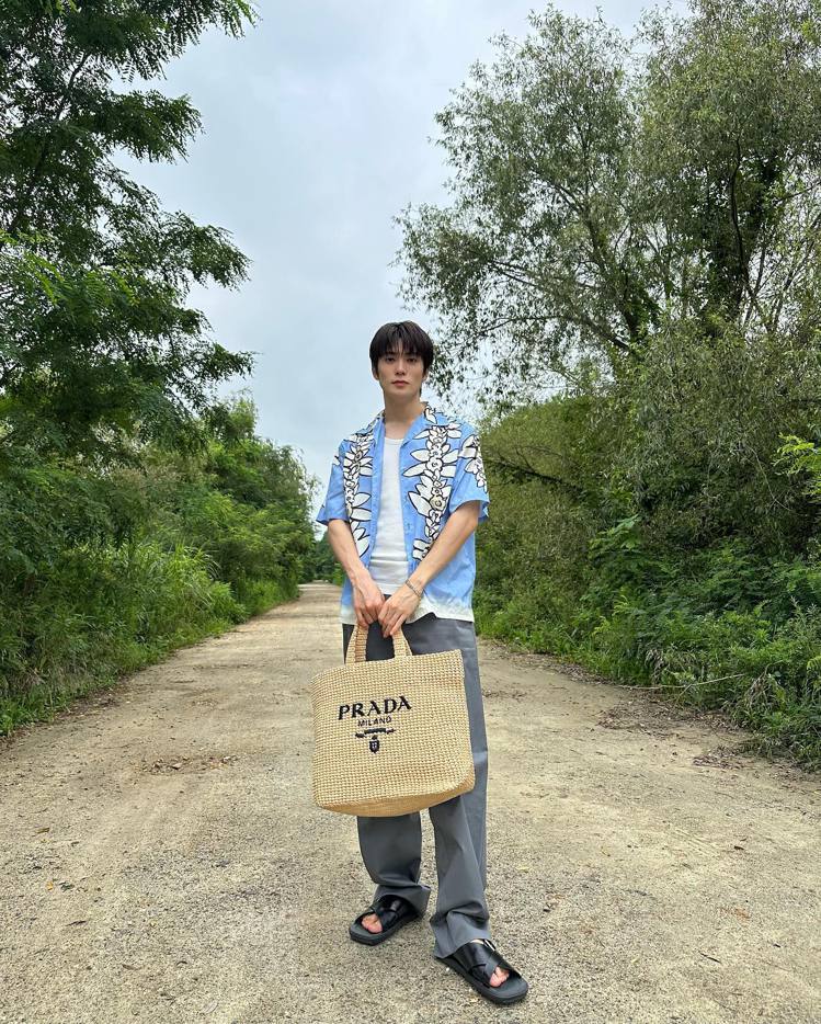 在玹以藍色襯衫、涼鞋搭配手上拉菲草編織包，完美展示渡假般的愜意心情。圖／翻攝自 IG @ _jeongjaehyun