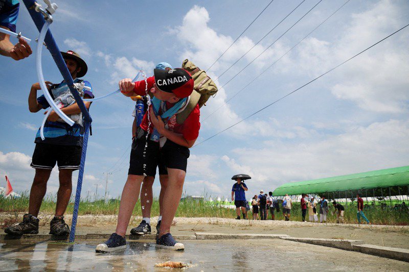 在韓國舉辦的世界童軍大會酷暑難耐，許多童軍紛紛想盡辦法解熱。（路透）