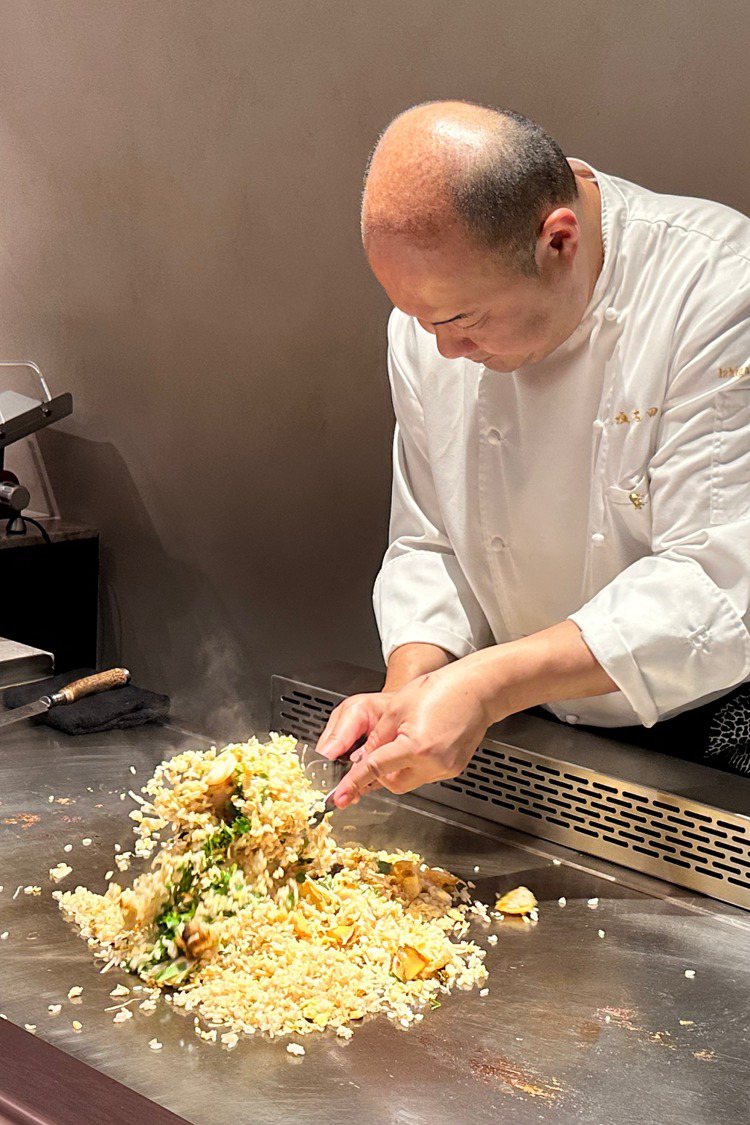 吉田純一在鐵板上迅速翻炒「鮑魚香菜炒飯」。記者高婉珮／攝影。