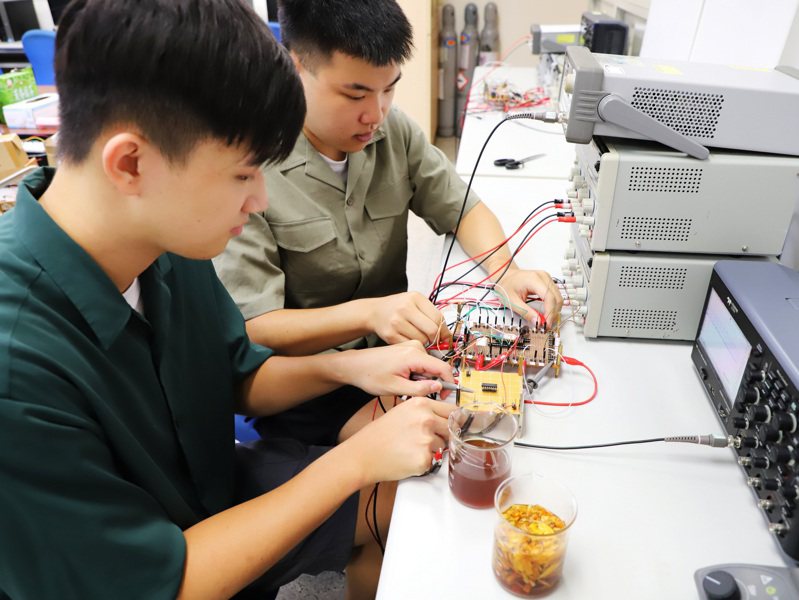嘉義大學電機工程學系學生吳翊誠（前）、楊書桓（後）在教授跨域指導下研發出「量測金針花中二氧化硫濃度偵測器」。圖／嘉義大學提供