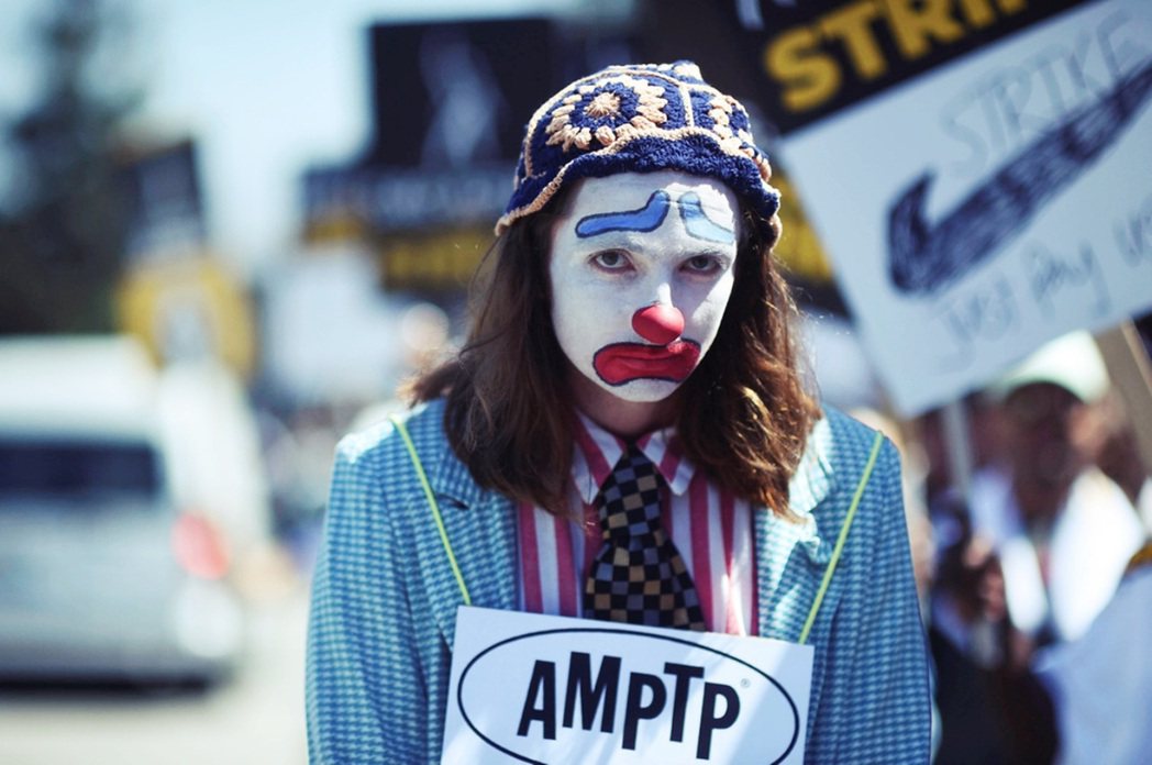 罷工示威中，示威人士打扮成小丑，並掛上美國電影和電視製片人聯盟（AMPTP）的牌...