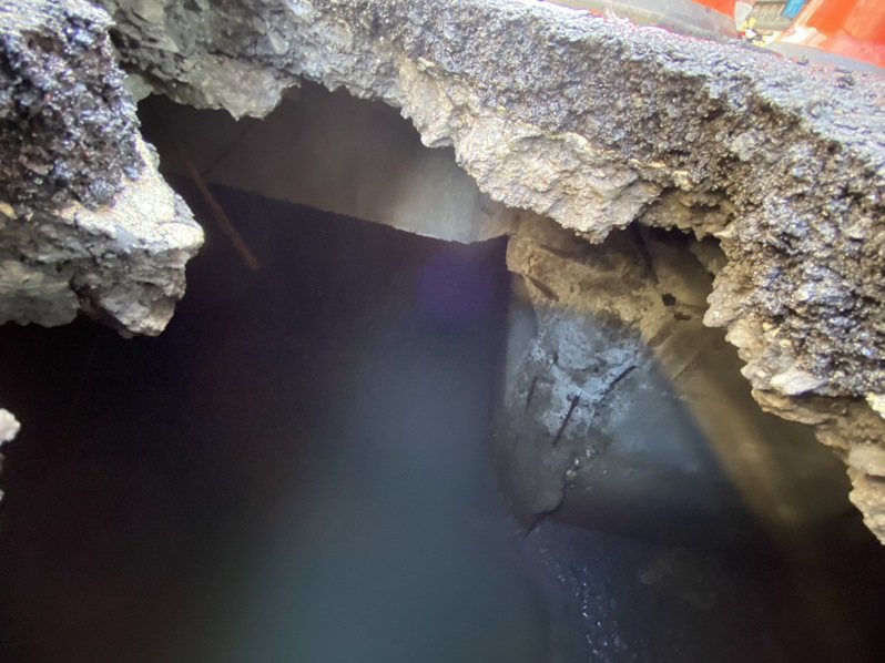 基隆市愛一路今天出現坑洞，下面就是旭川河，市府工務處封閉部分車道搶修。圖／基市府提供