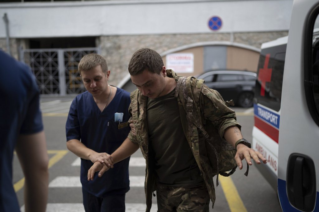 一名醫務人員幫助一名遭受砲彈攻擊的烏克蘭軍人進入烏克蘭第聶伯羅的梅奇尼科夫醫院。 圖／美聯社