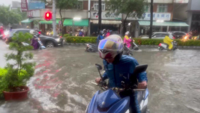 高雄市鳳山區澄清路因大雨積水，機車拋錨，騎士牽車涉水。圖／胡杉縈提供