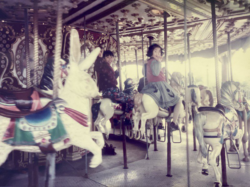 年幼的我與妹妹坐在遊樂園的旋轉木馬上。圖／川井深一提供