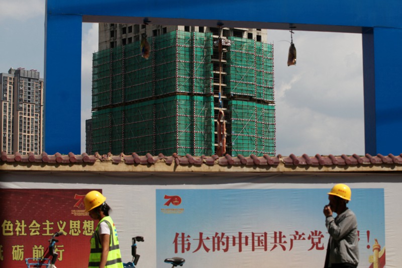 中國大陸房地產巨頭碧桂園也面臨資金鏈斷裂，該公司已預告今年上半年虧損超過人民幣450億元。圖為一名雲南昆明工人走過碧桂園住宅樓的建築工地。路透