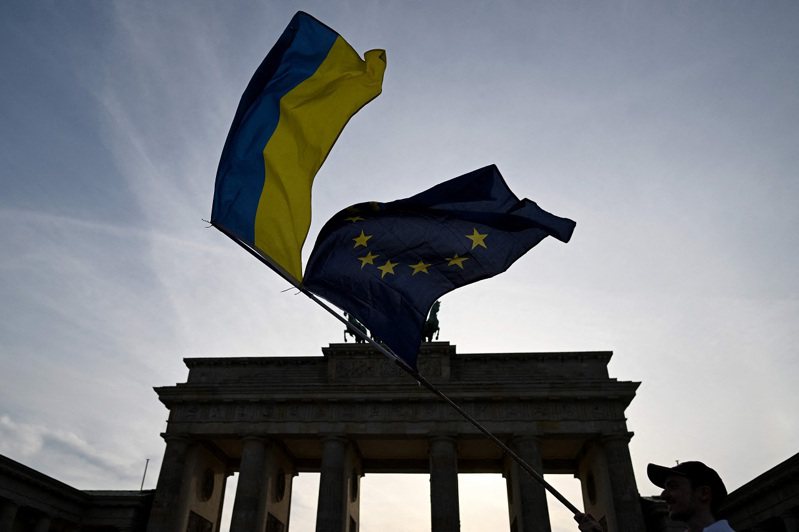 在8月24日烏克蘭獨立紀念日，一名倡議人士在德國柏林布蘭登堡大門前揮舞烏國和歐盟旗幟。法新社