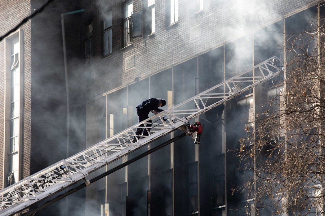 消防人員不斷噴射水柱嘗試控制火勢，大樓被濃煙燻黑。 圖／歐新社